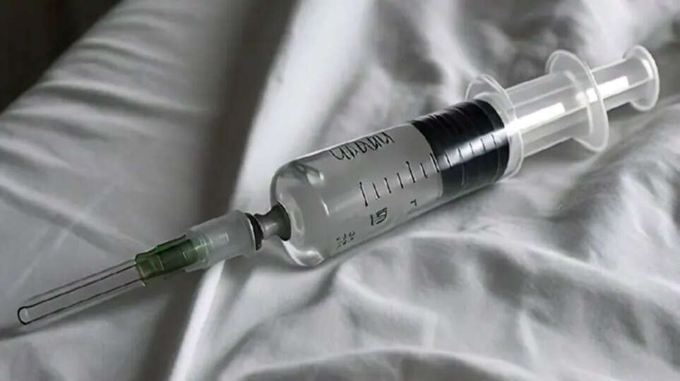 A syringe pricking a child's leg in a hospital setting