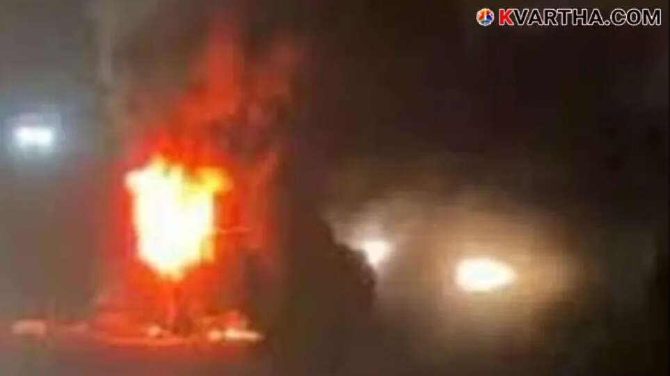 A tourist bus engulfed in flames in Maddur, Karnataka, with thick smoke billowing from the vehicle.