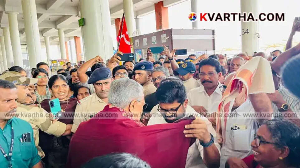 CPM Kannur District Secretary K.K. Ragesh wrapping a traditional red shawl around Leader of the Opposition Pinarayi Vijayan at the airport arrival terminal.