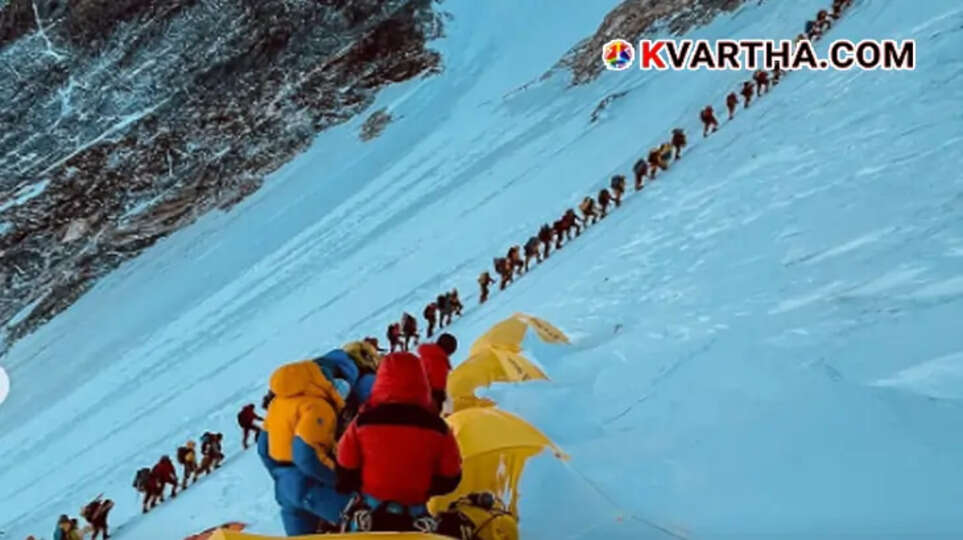  Line of international mountaineers with heavy gear climbing the snowy slopes of Mount Everest