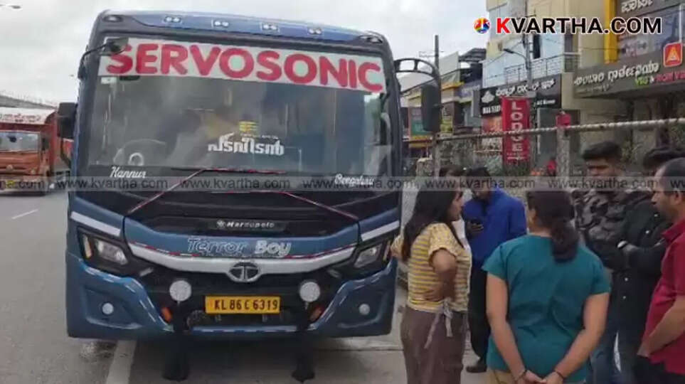 A private bus broken down on the Mysore-Bengaluru bypass road with passengers waiting outside.