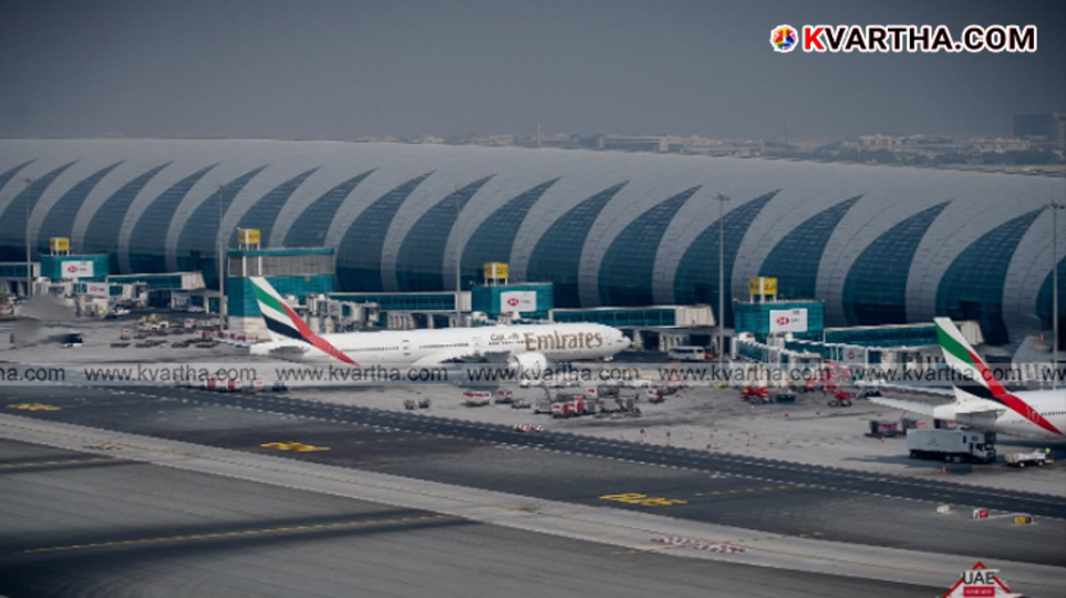 Passengers checking flight status on a large screen at Dubai airport.