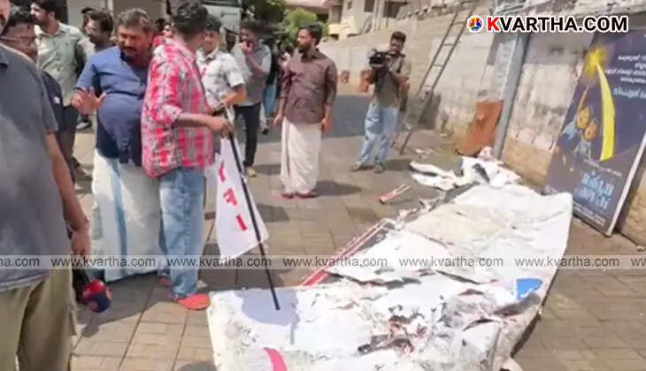 DYFI activists holding red flags and protesting in front of a theater.