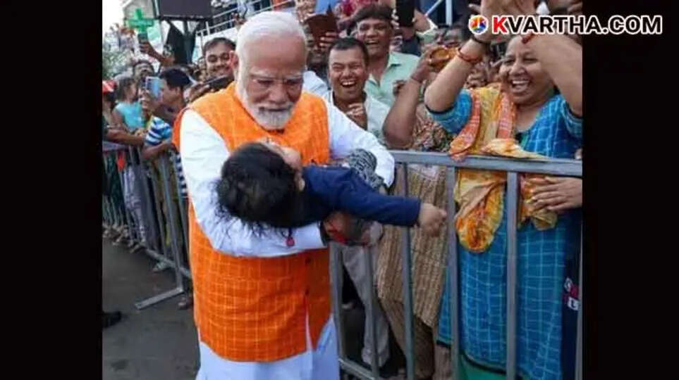 PM Modi cradles a baby in his arms after casting his vote in Ahmedabad