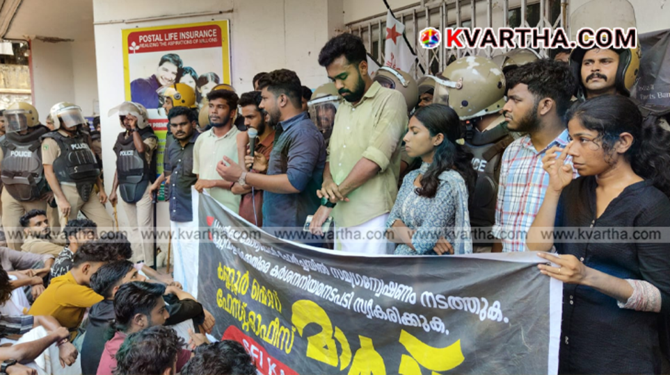 SFI activists waving flags and jumping over police barricades during a protest in Kannur.