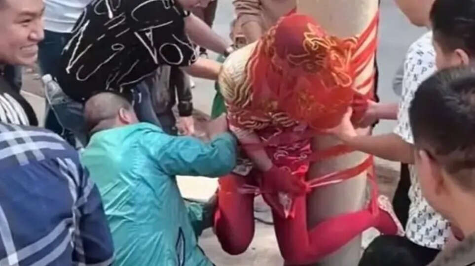 A bride tied to a pole during a Chinese wedding ceremony.