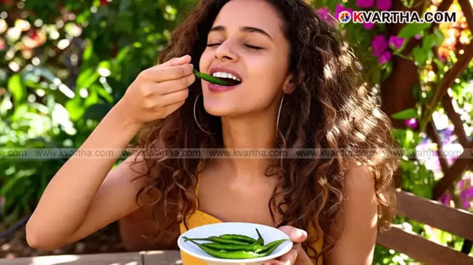 A bunch of fresh green chillies on a wooden surface.