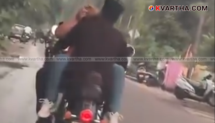 A couple performing a dangerous stunt on a bike.