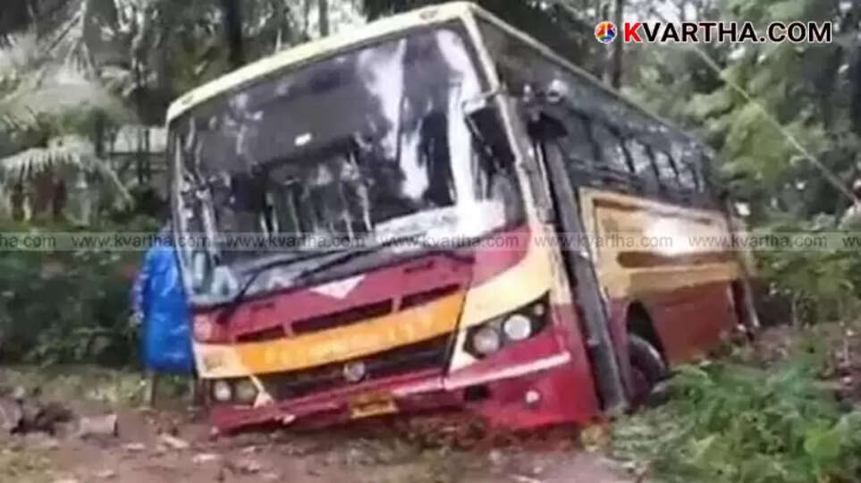 A KSRTC bus partially submerged in a waterlogged area beside a road.